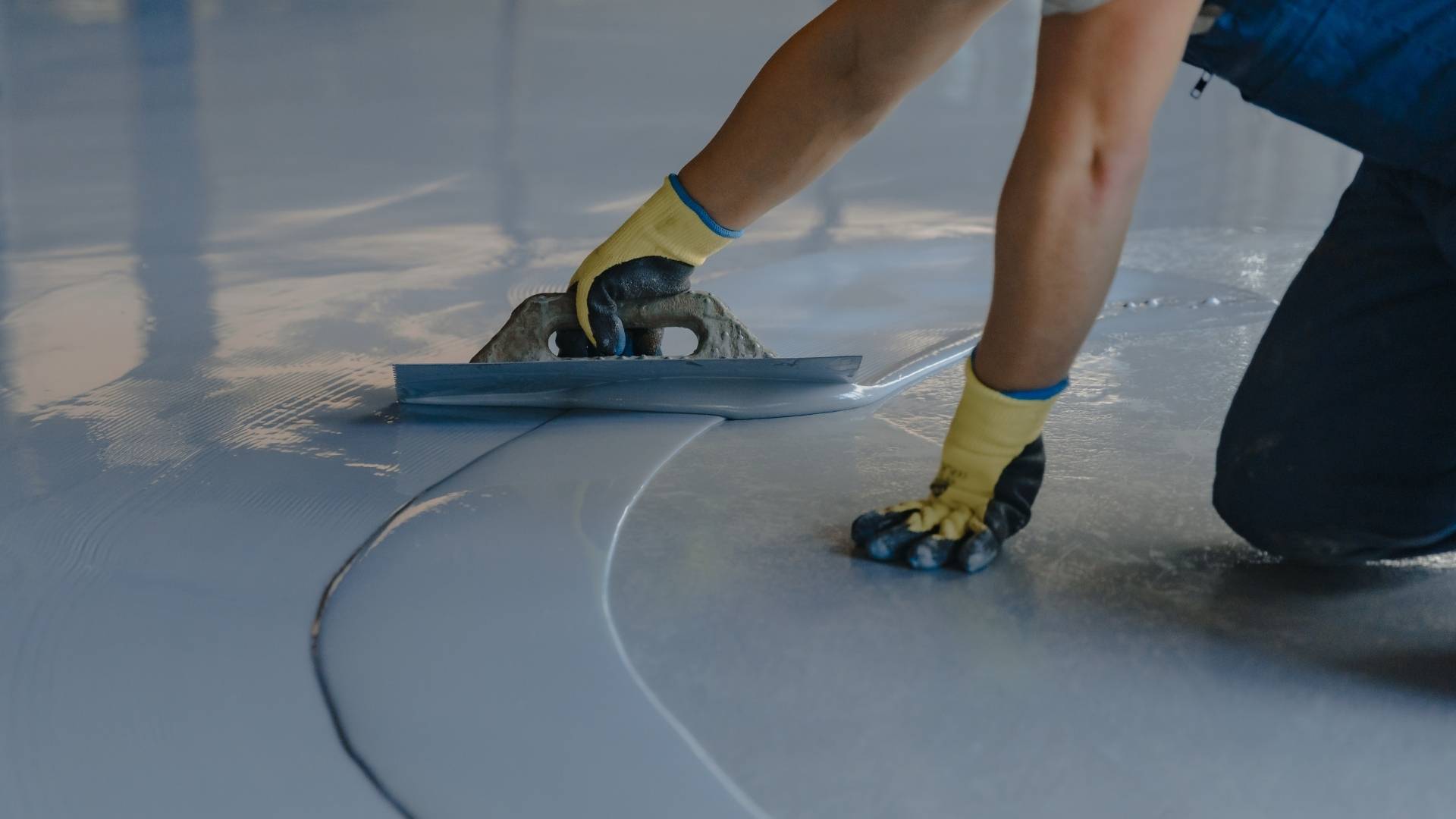 Worker smoothing wet concrete floor with trowel
