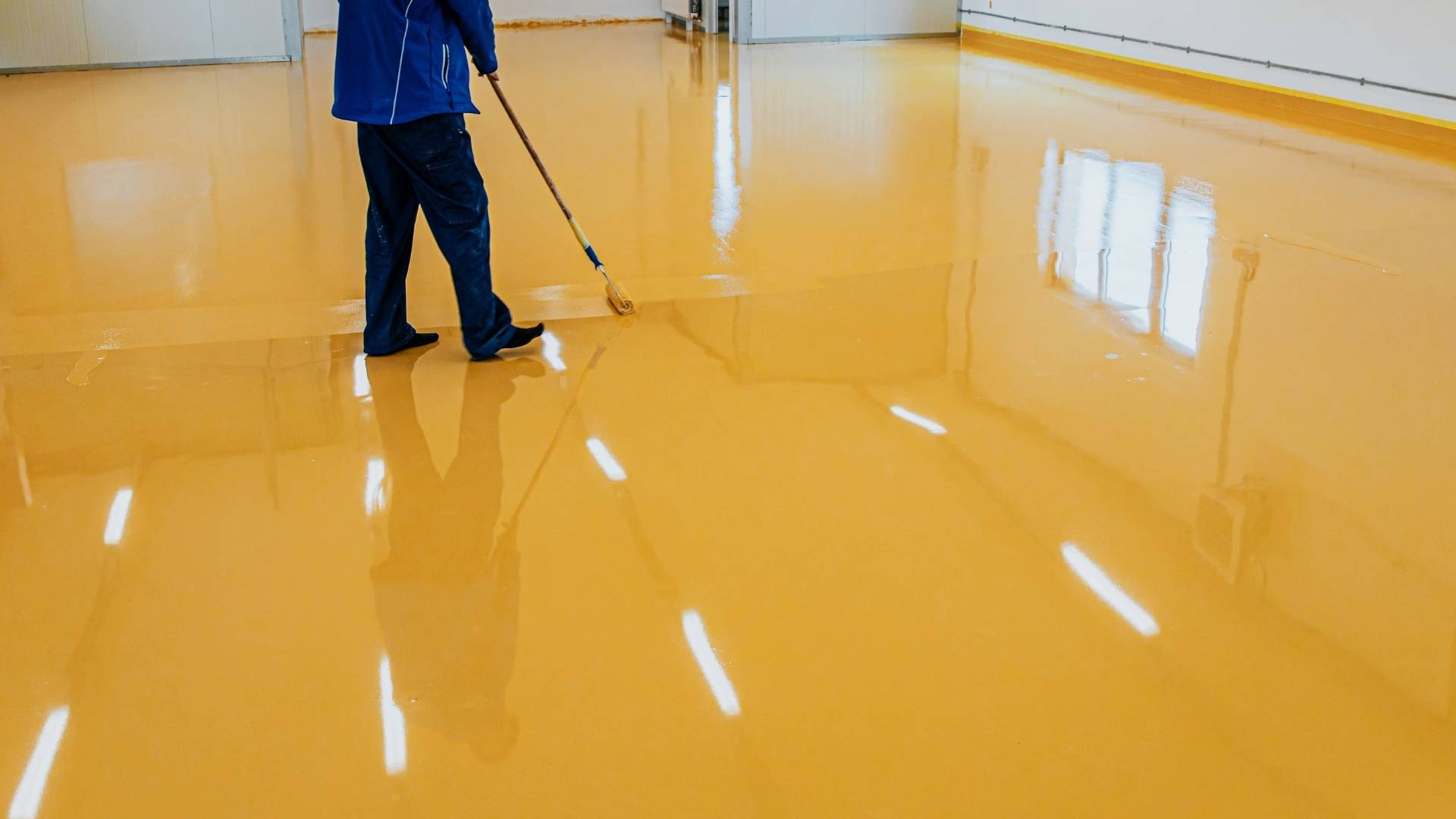 Worker applying yellow epoxy floor coating