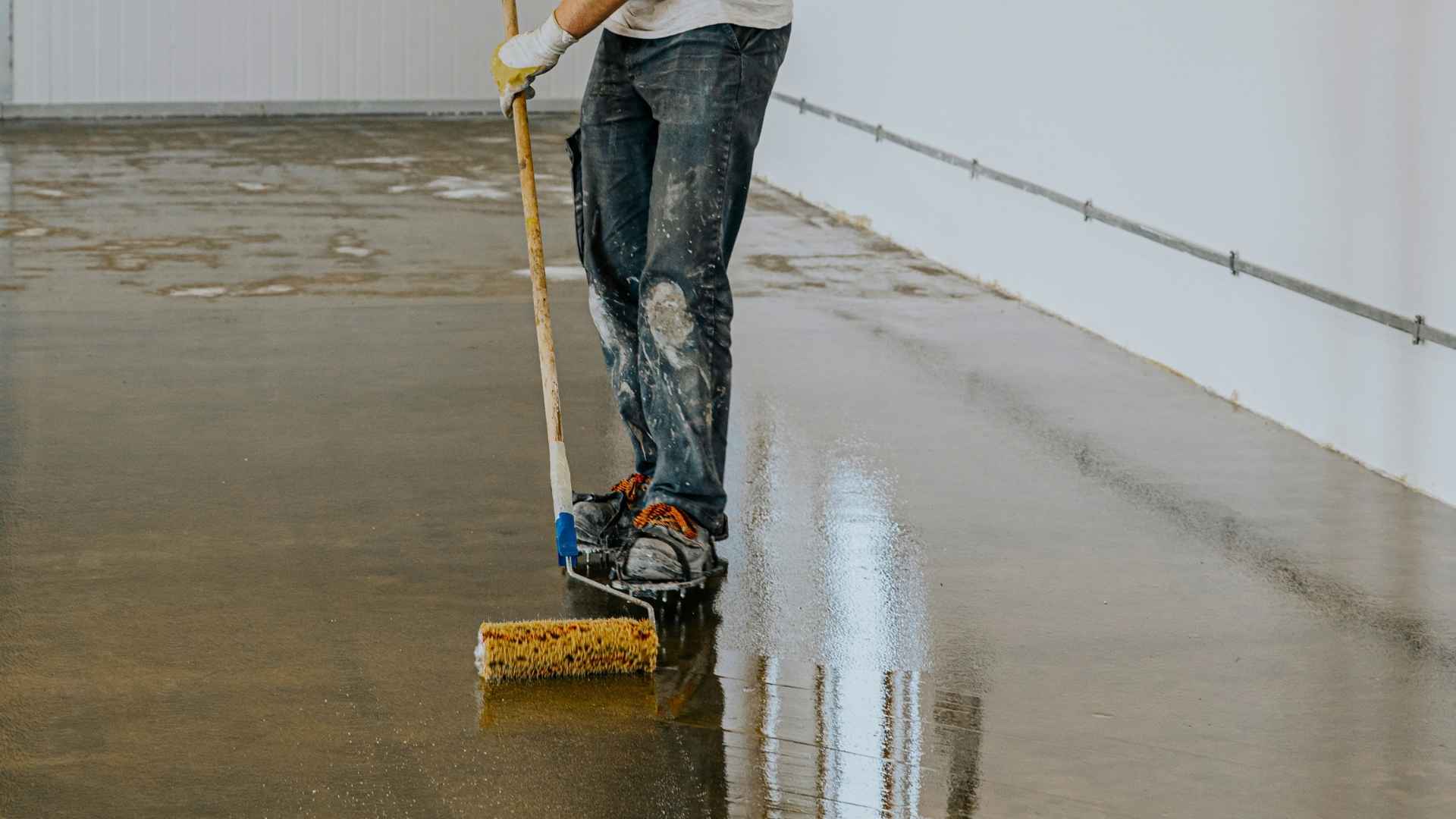 Person applying epoxy on concrete floor.