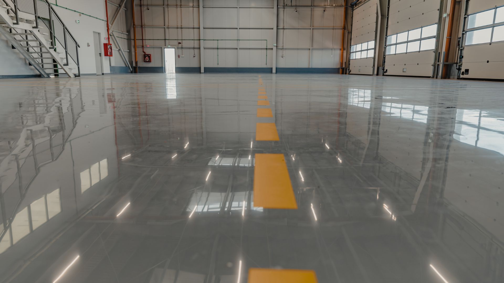 Empty indoor warehouse with glossy floor and yellow line.