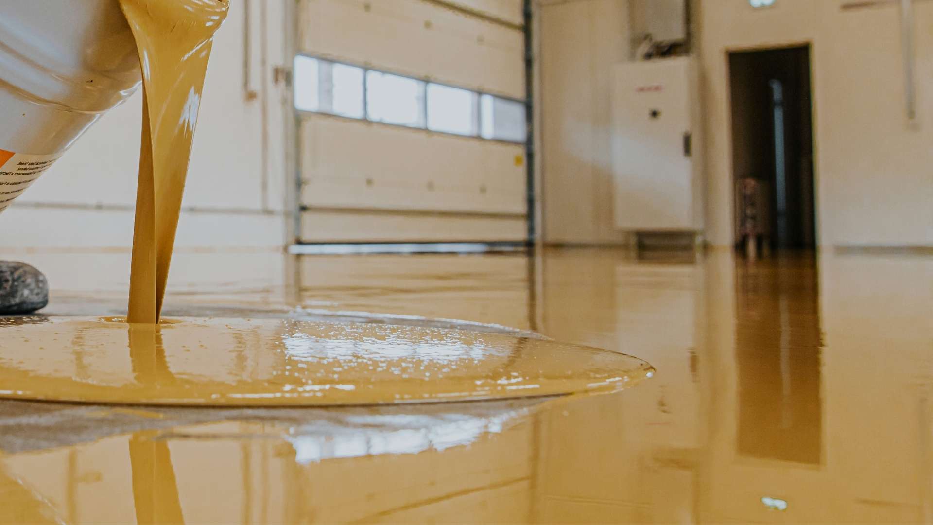 Yellow epoxy coating being poured on garage floor